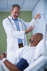 Fototapeta premium Doctor interacting with patient while adjusting iv drip