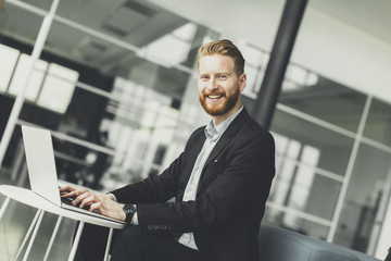 Attractive businessman typing on his laptop at the office