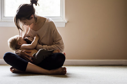 Woman breastfeeding son while sitting at home