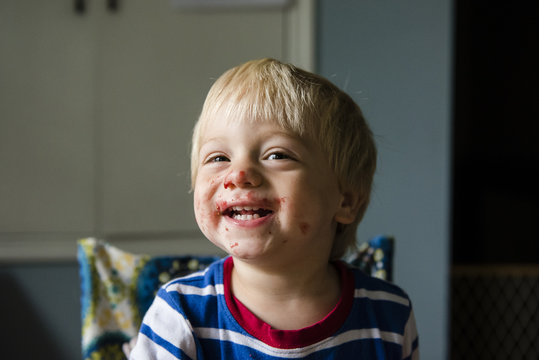 Cheerful Boy With Messy Face Sitting At Home