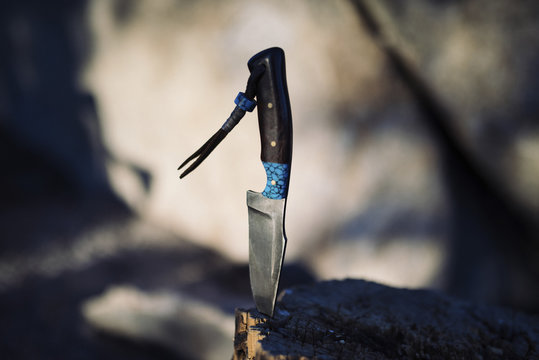 Close up of knife stuck on wooden log 