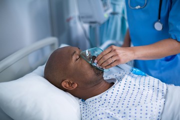 Nurse adjusting oxygen mask on patient mouth - Powered by Adobe