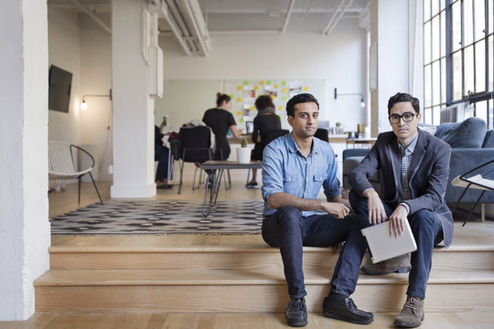 Portrait Of Business People With Digital Tablet Sitting On Steps