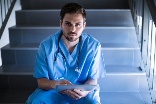Portrait of male nurse sitting on staircase 