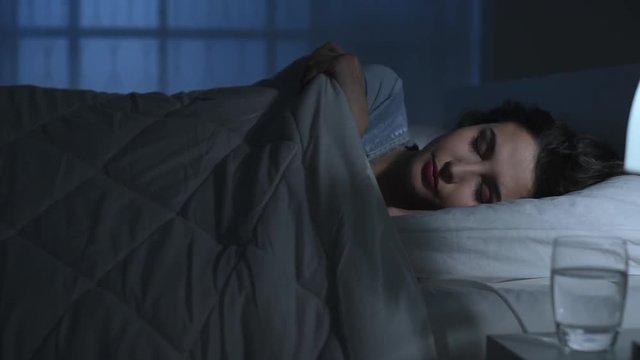 Young woman sleeping in her bed at night under a soft duvet