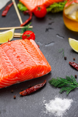 Fresh red fish (salmon fillet) and tomatoes, lime and chili pepper are ready for cooking.