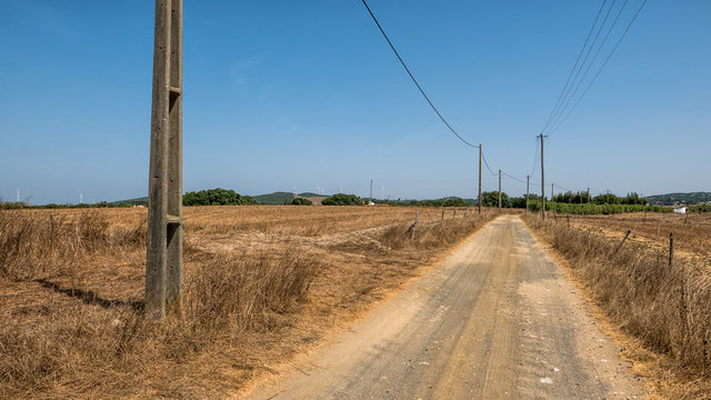 Ländliche Schotterstraße im Algarve mit Stromleitungen