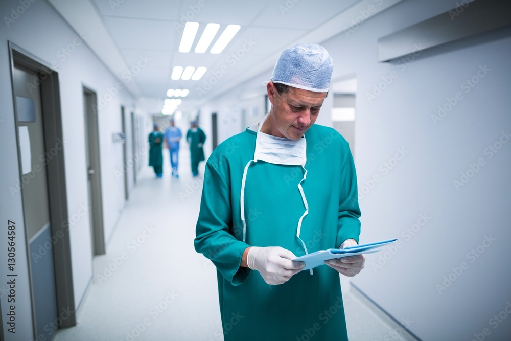 Poster surgeon checking report in corridor