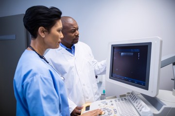 Doctor and nurse using patient monitoring machine in ward