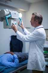 Male doctor sets up the machine to x-ray over patient