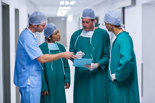 Surgeons and nurse having discussion on file in corridor
