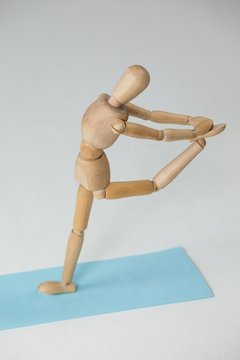 Wooden figurine exercising on exercise mat