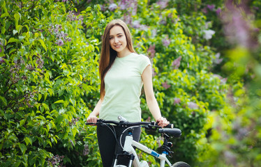 Naklejka premium Happy young girl cyclist standing with a mountain bike and. Adventure travel. Girl cyclist. Mountain bike. healthy lifestyle. Sort concept.