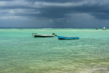 Two old fishing boats in clear sea with a stormy background