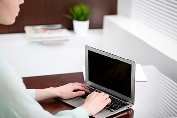 Fototapeta premium Business woman hands in a green blouse sitting at the desk in the office and typing on the laptop .