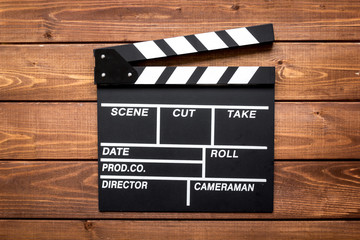 Screenwriter desktop with movie clapper board wooden background top view
