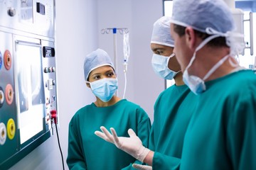 Surgeons discussing a report on surgical monitor 