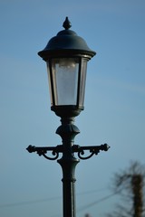 Head of an old fashioned victorian style lampost against a blue sky