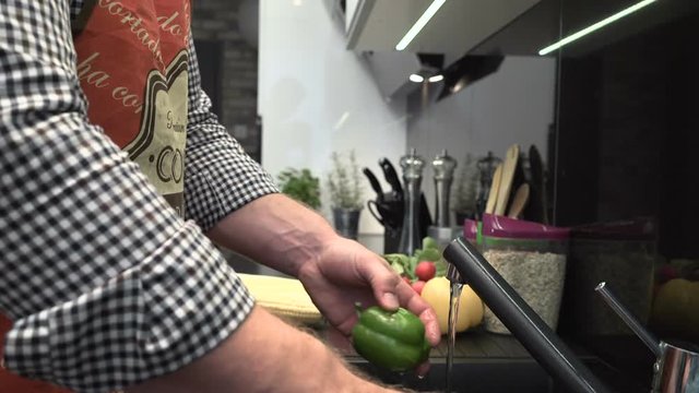 Close up on man's hands washing peppers.
