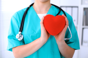 Female surgeon doctor with stethoscope holding heart.
