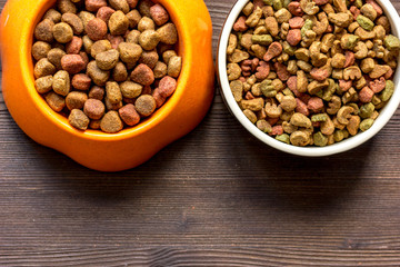 dry dog food in bowl on wooden background top view