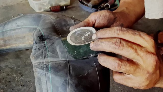 closeup macro man hands put patch on motorcycle wheel inner tube and stick it strong and fast in repair-shop
