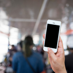 Woman hand holding and using mobile,cell phone,smart phone with isolated screen with blur image of people for background.