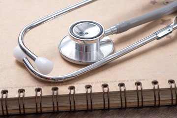 Medical concept : stethoscope on note book with wood background