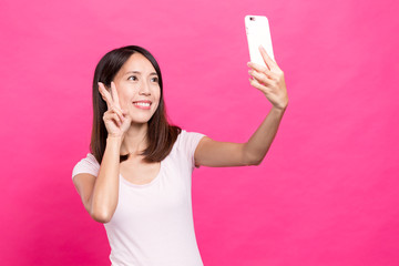 Naklejka premium Young woman take selfie by mobile phone