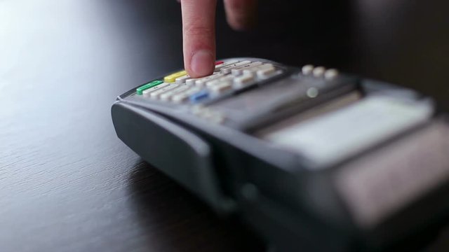 Buyer makes the payment by credit card. Credit Card Terminal. Man's hand pushing the button and swipe credit card payment.