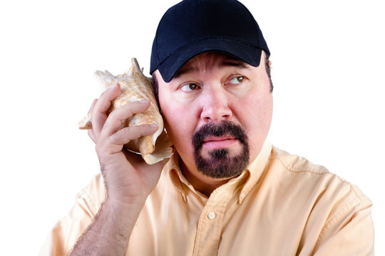 Man listening to sound of sea in shell