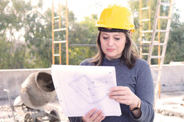 Female architect at a construction site with blueprints.