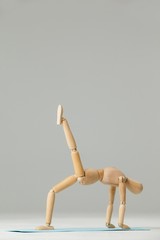 Wooden figurine exercising on exercise mat