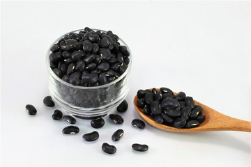  glass bowl full of black small beans with a wooden spoon glass