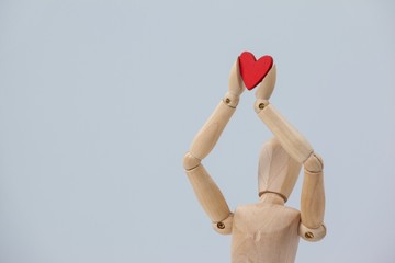 Wooden figurine holding a red heart on top