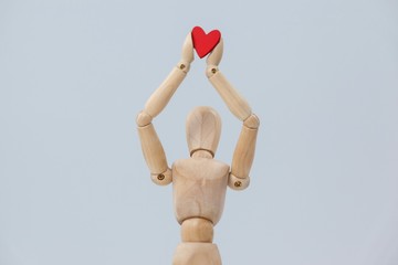 Wooden figurine holding a red heart on top