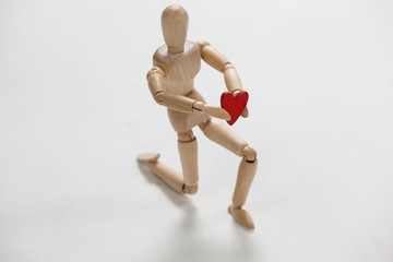 Wooden figurine kneeling and holding a red heart