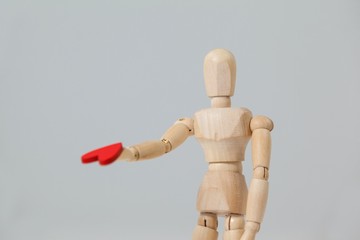 Wooden figurine standing and giving a red heart