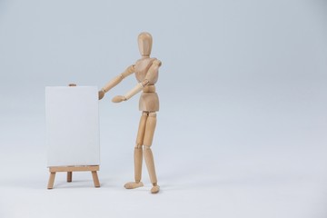 Wooden figurine standing next to white board 