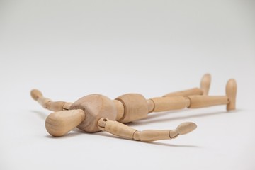 Wooden figurine lying on floor with arms spread
