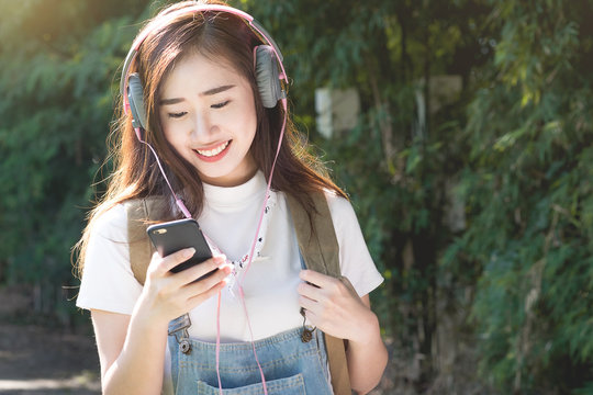 Young asian hipster wear headphone listening to music through sm