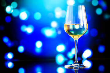 glass of white wine against a glowing bokeh - copy space, select
