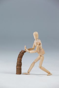 Wooden figurine preventing stack of coins from falling