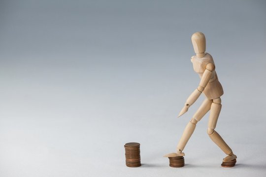 Wooden figurine stepping on stack of coins