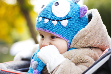 Kid in a funny hat. The boy walks in the fresh air. The kid is playing in the yellow leaves
