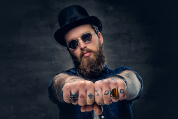 Close up tattooed hipster's fingers with rings.