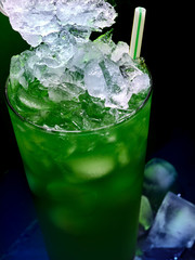 Alcohol cocktail in bar. Close up of frozen alcohol cocktail on black background. Green mixed drink with straw. Top view of aperetif.