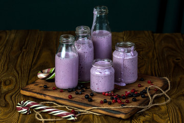 Set of blueberry smoothies in the different size jars on wood background