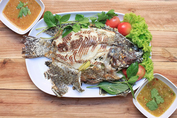 Tilapia fish grilled with Salt in white dish and have Spicy Sauc
