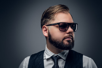 Bearded  male in sunglasses wearing waistcoat and bow tie.